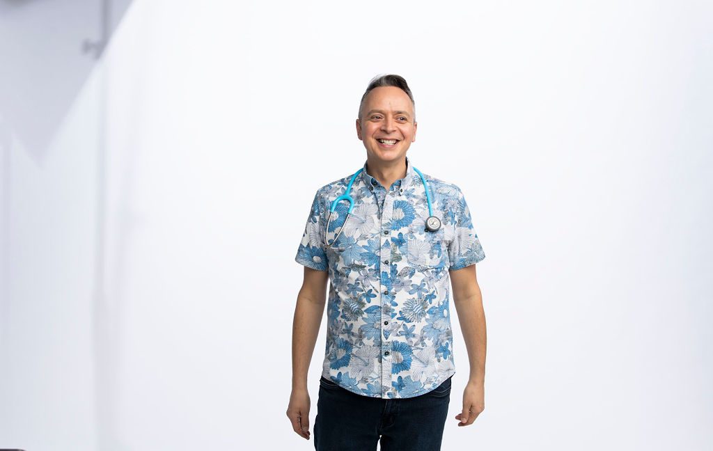 Marcus Greatheart standing in a floral shirt with a stethoscope around his neck