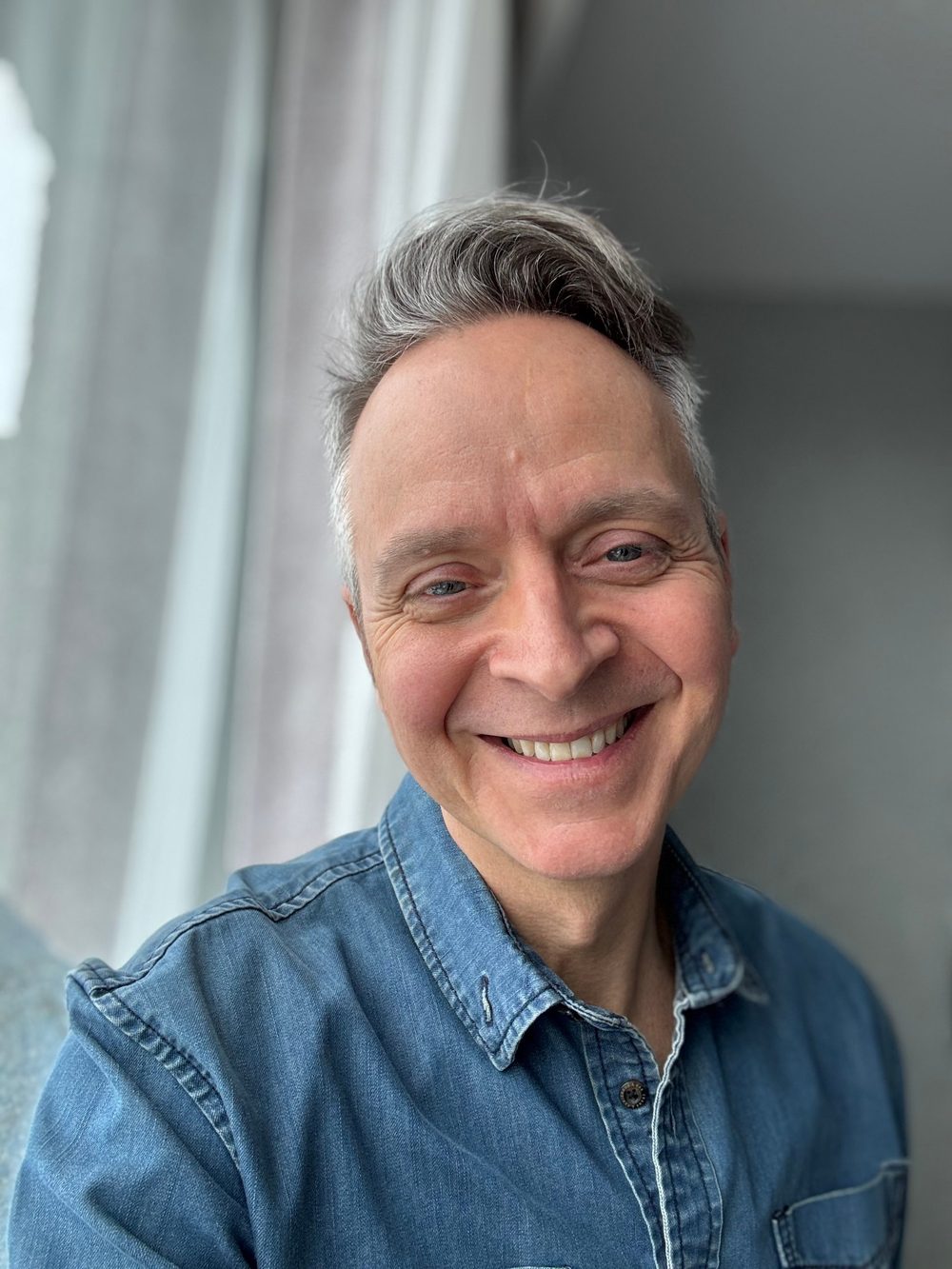 Marcus Greatheart smiling, wearing a denim shirt